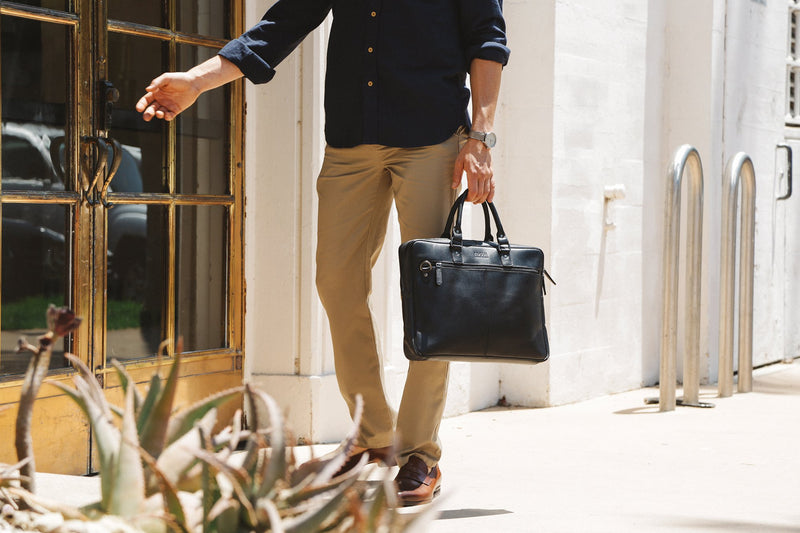 A man in a tan shirt holding a Tradevia West End Slim Leather Laptop Bag.